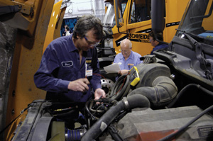 Two Schneider National, Inc. maintenance technicians perform diagnostic service on an engine.