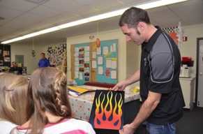 PPG painter Jason Lutton displays a flame-painted panel to Hudson School students