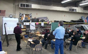 Techs Of Tomorrow Instructor, Bill Harris of ERS (in dark-striped shirt) instructing Parma Senior High School (Parma, OH) Collision Instructor Alan Bradny’s class about Personal Protection Equipment.   